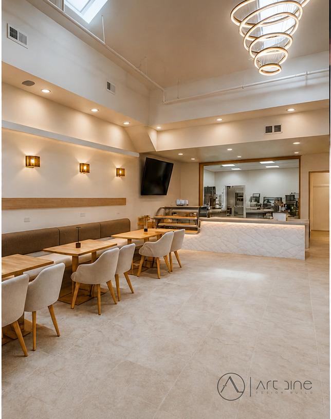 Completed cafe buildout with service counter, dining seating, skylight, and modern lighting